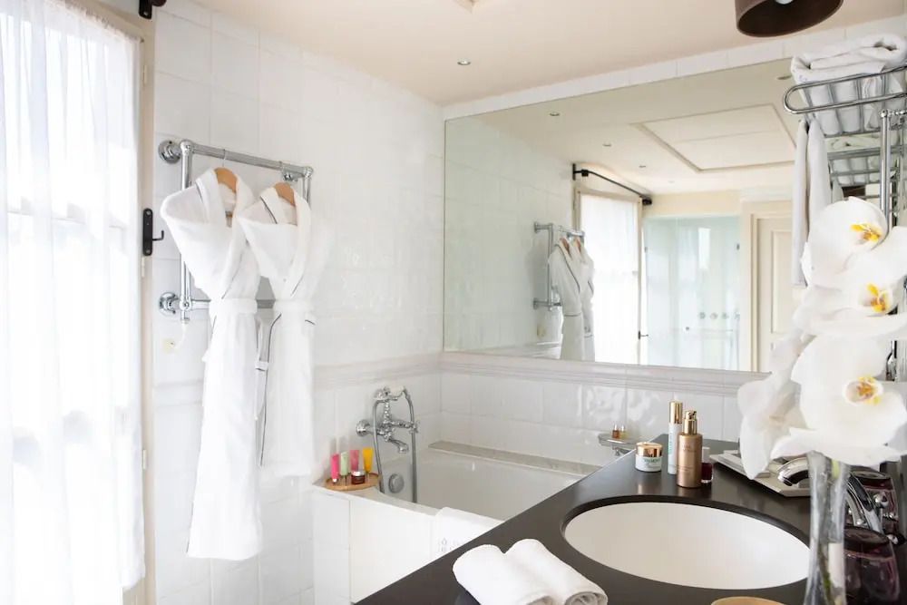 Luxuriöses Badezimmer mit Badewanne, großem Spiegel und eleganten Annehmlichkeiten.