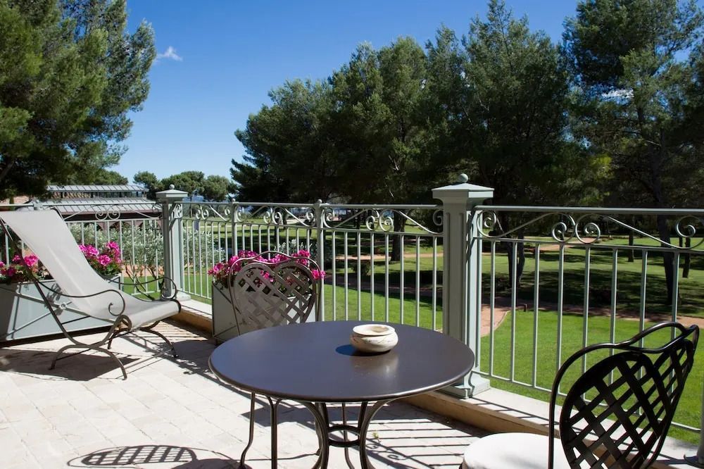 Terrasse mit Sitzgelegenheiten und Blick auf gepflegten Garten bei sonnigem Wetter.
