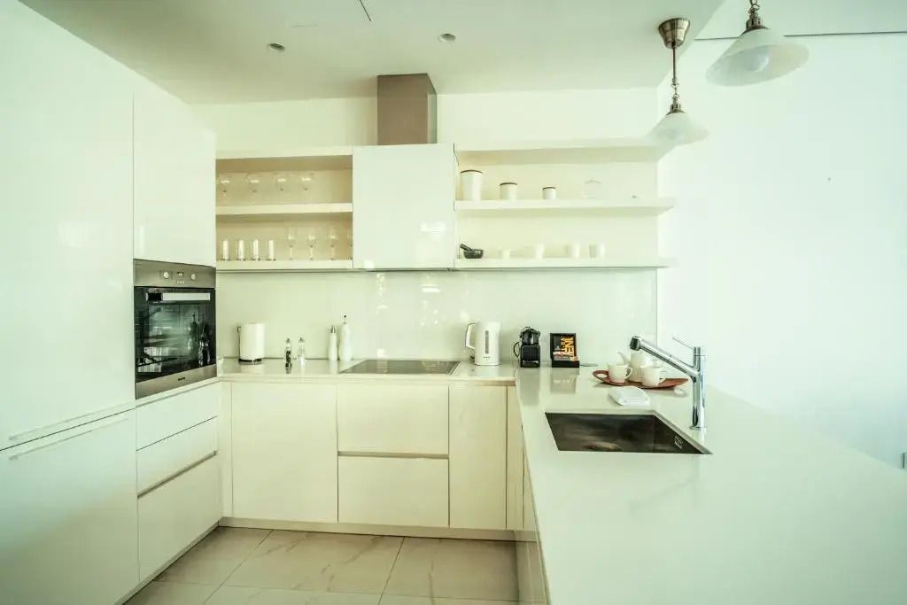 Moderne offene Küche mit weißen Schränken und integrierten Geräten im Deluxe Apartment
