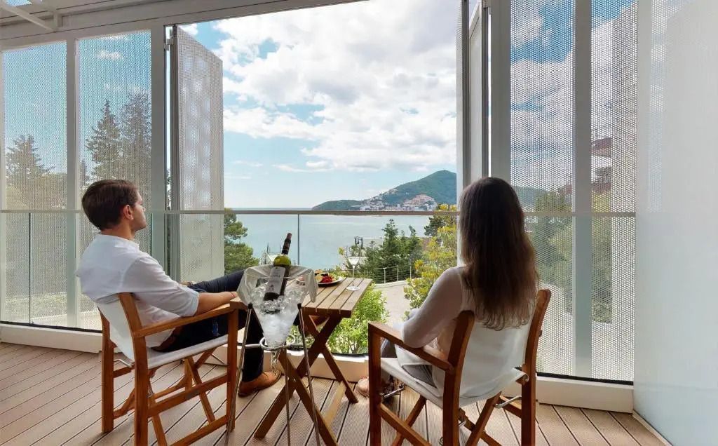 Paar auf Balkon mit Blick auf die Küste und Berge