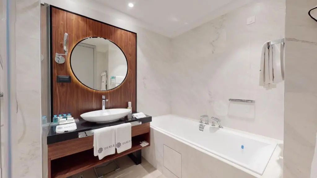 Luxuriöses Badezimmer mit runder Spiegelanordnung und Badewanne