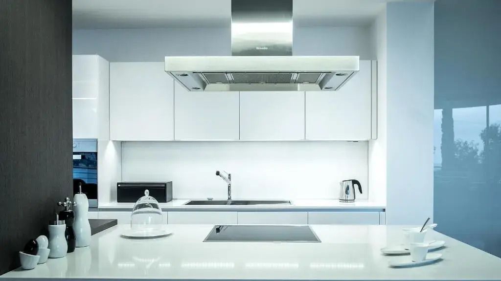 Moderne weiße Küche mit Edelstahlgeräten und minimalistischem Design