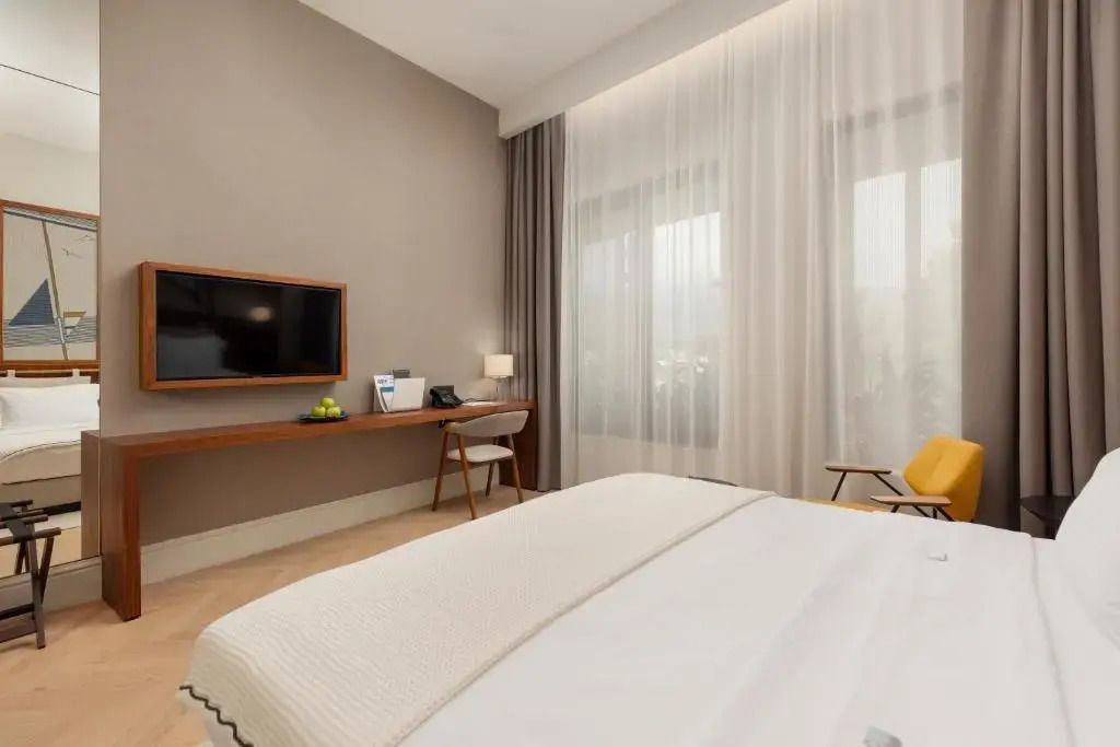 Modernes Superior Zimmer mit Schreibtisch und großem Fenster im ĀNANTI Resort