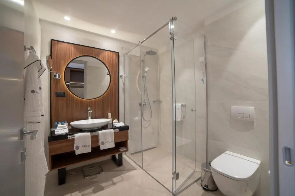 Luxuriöses Badezimmer mit Glasdusche und Holzvertäfelung im ĀNANTI Resort