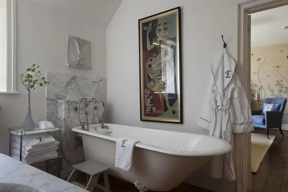 Elegantes Badezimmer mit freistehender Badewanne und Kunstwerken an der Wand