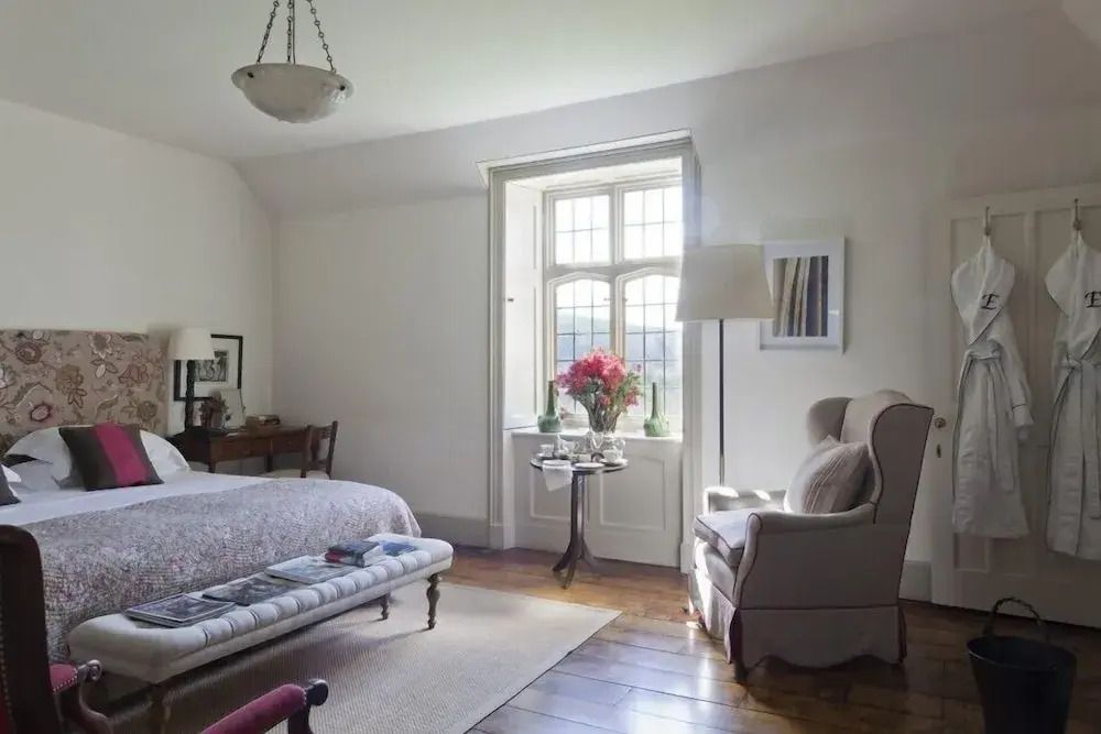 Gemütliches Schlafzimmer mit Fenster, Sessel und Blumen auf dem Tisch