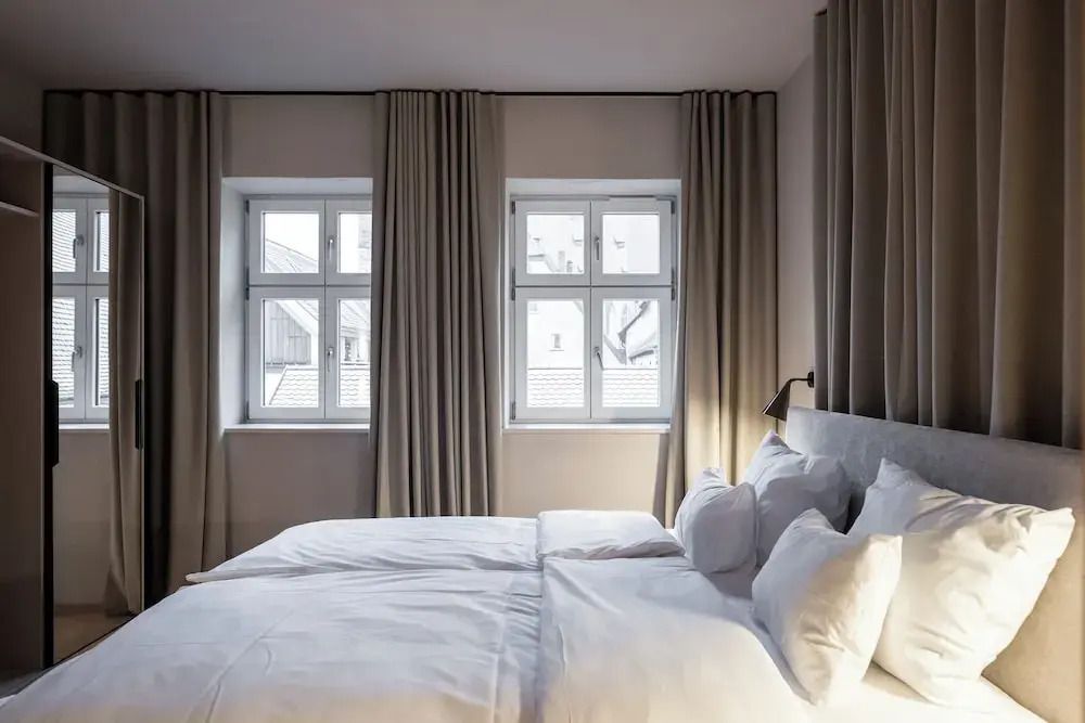 Gemütliches Schlafzimmer mit Doppelbett und großen Fenstern