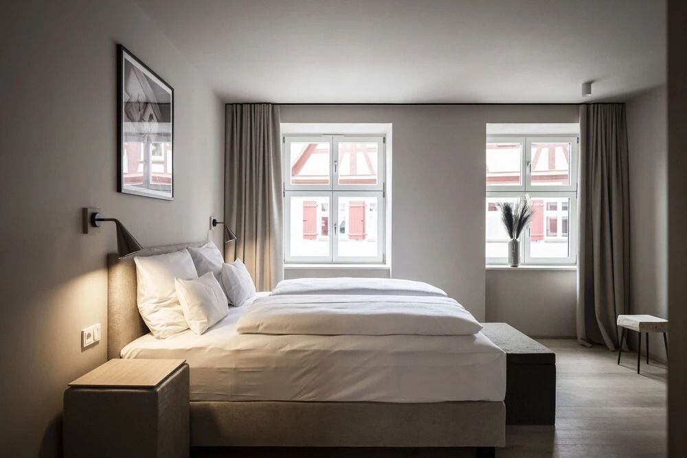 Helles Schlafzimmer mit Doppelbett und großen Fenstern