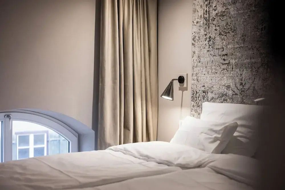 Luxuriöses Bett in einer Suite mit Vorhang und stilvoller Wand