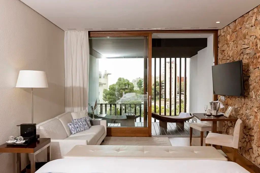 Helles Hotelzimmer mit großzügigem Balkon und Ausblick in die Natur