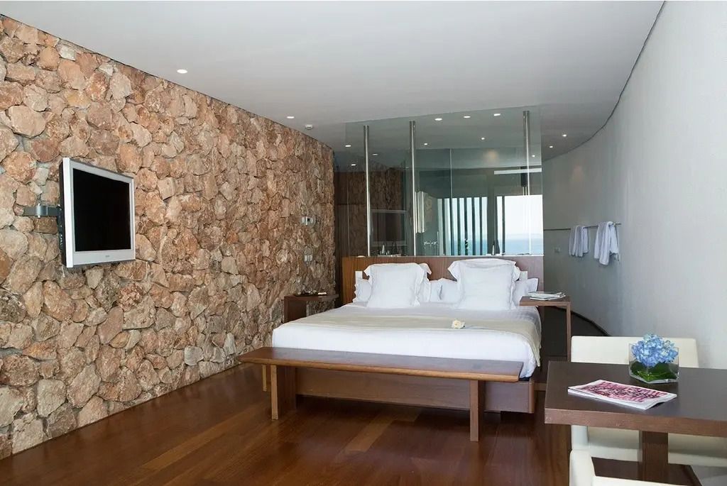 Luxuriöses Schlafzimmer mit Holzboden und Natursteinwand in einer Hotelsuite