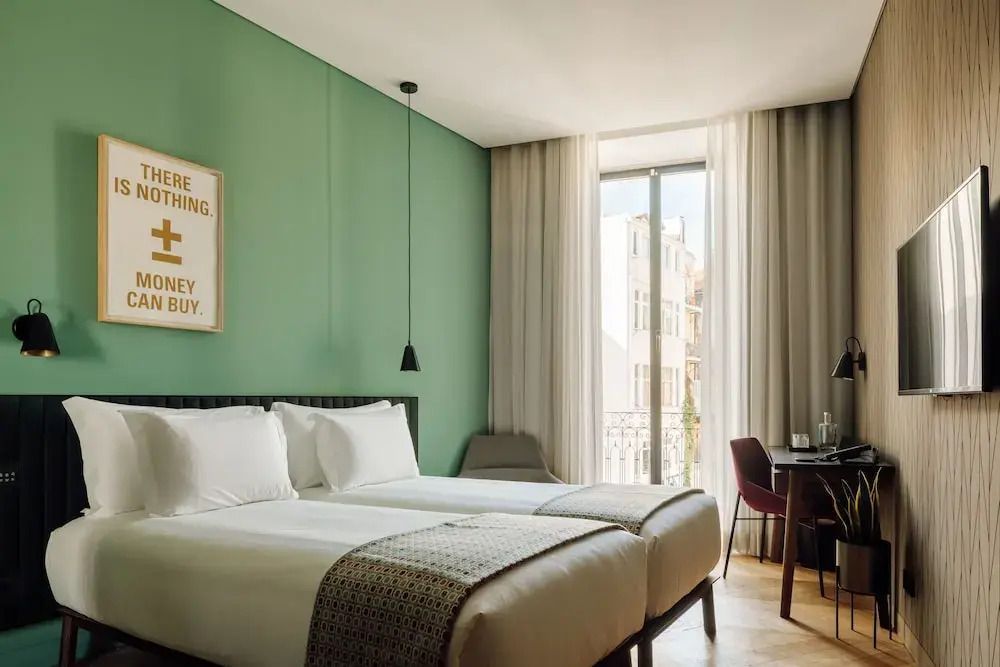 Modernes Doppelzimmer mit grüner Wand, zwei Einzelbetten und Balkonblick im Hotel.