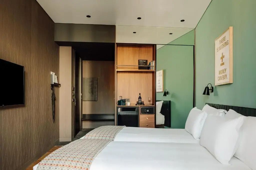 Zimmeransicht mit Spiegel, Minibar und zwei Einzelbetten in modernem Design.