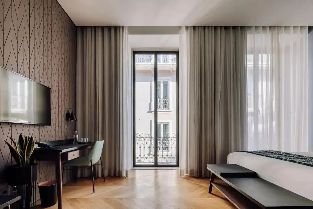 Zimmer mit Schreibtisch und großem Fenster mit Vorhängen