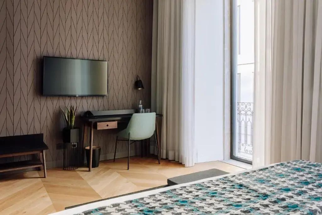 Hotelzimmer mit Schreibtisch und Fernseher gegenüber dem Bett