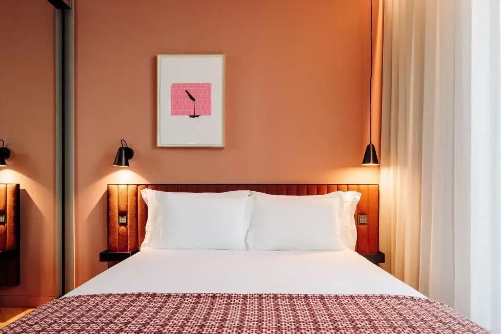 Gemütliches Doppelbett mit weißen Kissen und stilvollen Wandleuchten in einem modernen Zimmer
