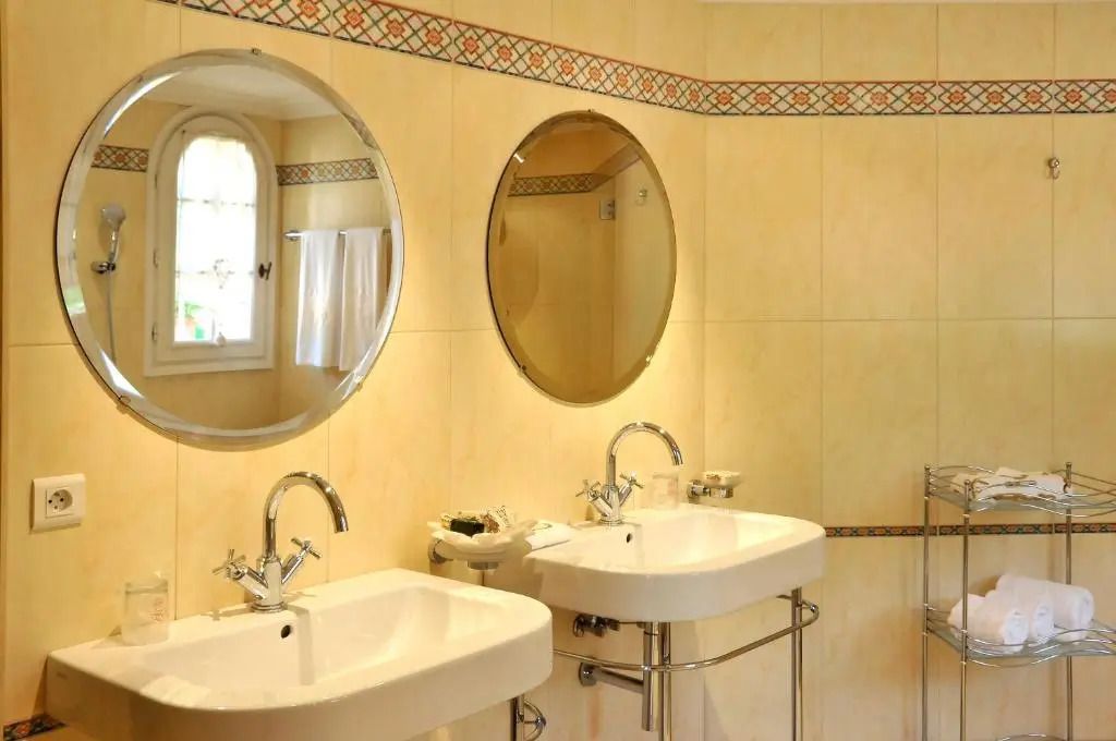 Modernes Badezimmer mit zwei Waschbecken und runden Spiegeln.