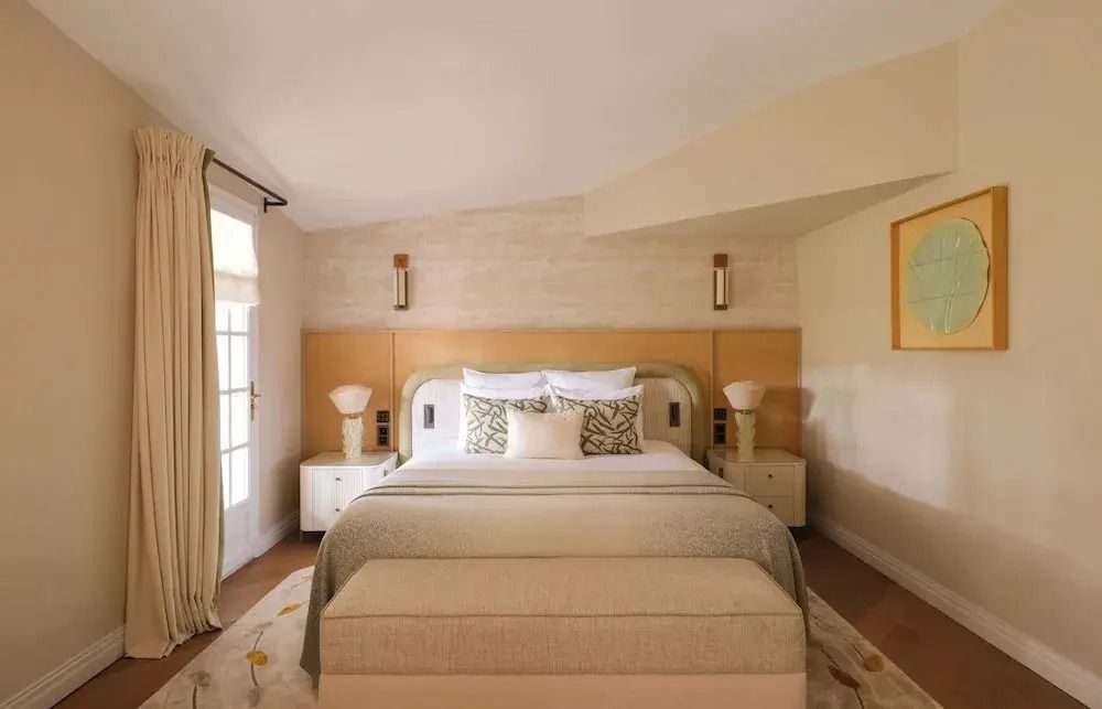 Helles Hotelzimmer mit luxuriösem Doppelbett und direktem Zugang zum Balkon.