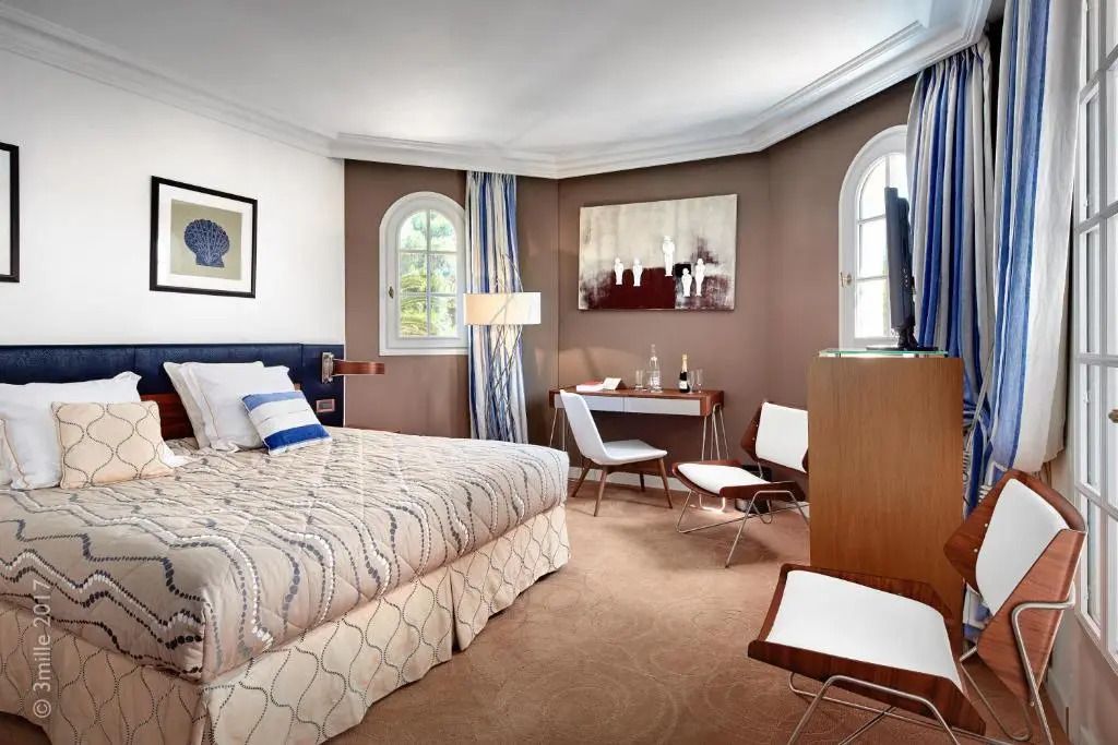 Helles Schlafzimmer einer Junior-Suite mit Doppelbett und Schreibtisch