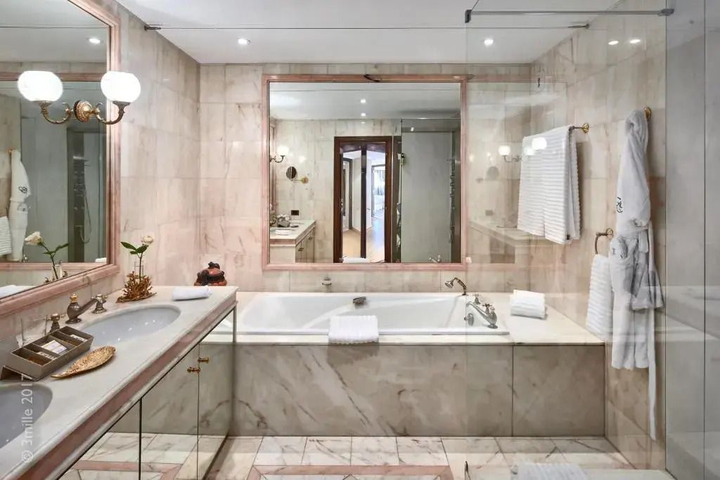 Luxuriöses Badezimmer mit Marmorwänden und großer Badewanne