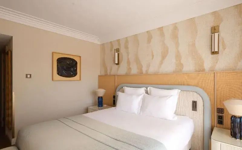 Helles Zimmer mit Doppelbett, Kunstwerk und dekorativer Wand.
