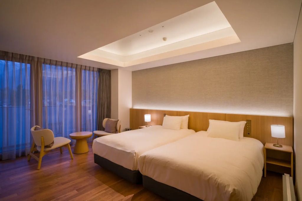 Modernes Hotelzimmer mit zwei großen Betten und bodentiefen Fenstern