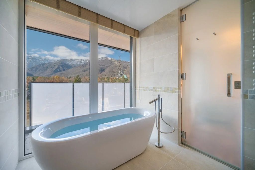 Freistehende Badewanne mit Blick auf die Berge durch große Fenster