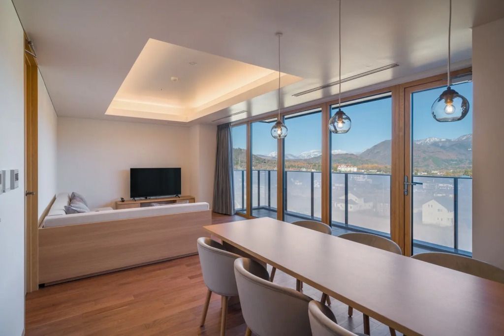 Wohnzimmer mit Esstisch, Fernseher und Blick auf die Berge durch große Fenster