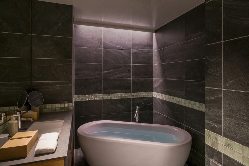 Elegante Badewanne in modernem Badezimmer mit dunklen Fliesen