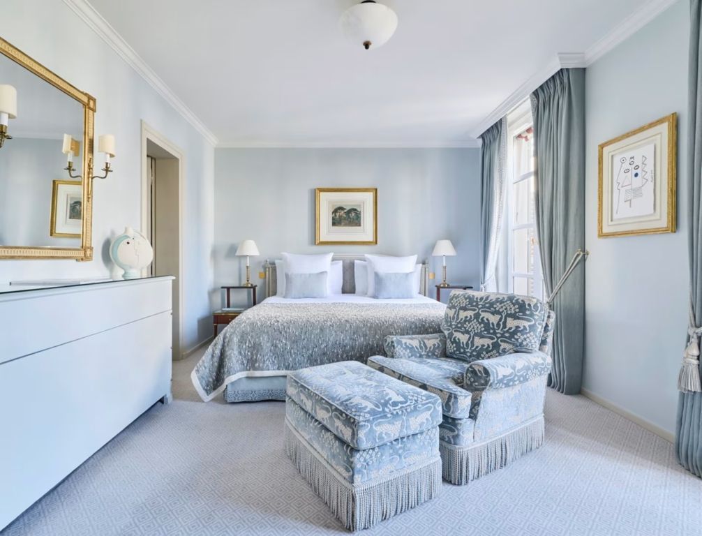 Elegantes Schlafzimmer in Pastelltönen mit Doppelbett und gemütlichen Sesseln
