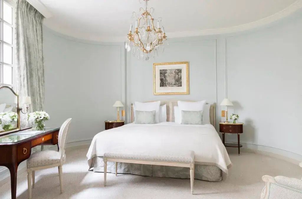 Geräumige Suite mit elegantem Kronleuchter und komfortablem Doppelbett.