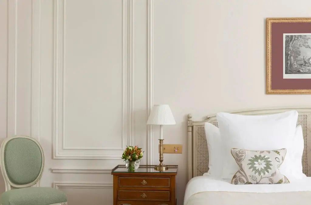 Nachttisch mit stilvoller Lampe und Blumenarrangement neben einem Bett