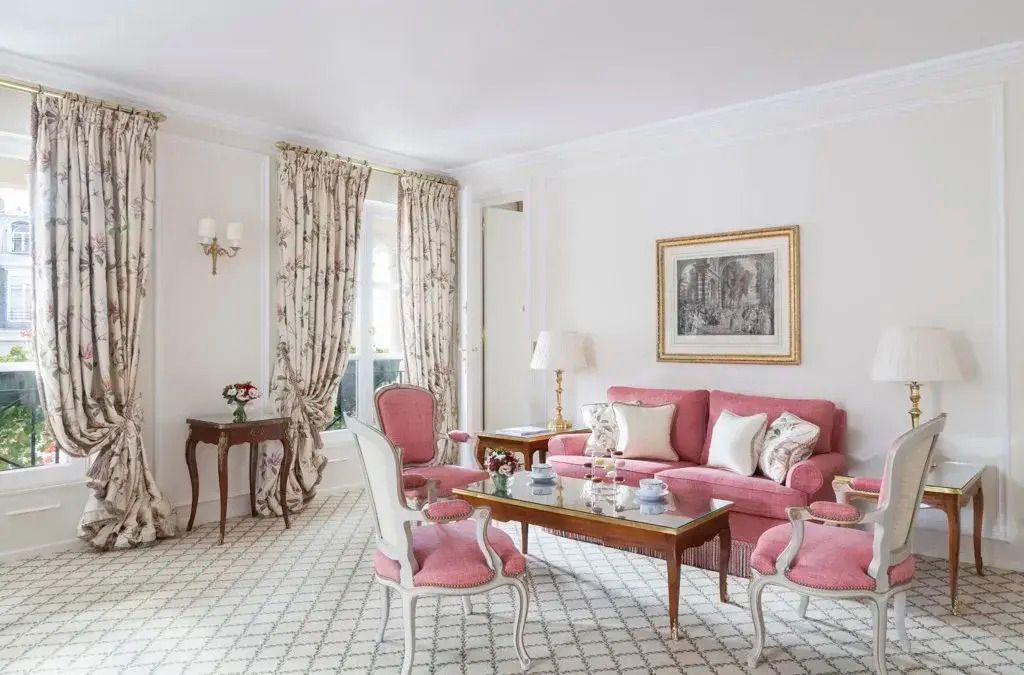 Helle Suite mit rosa Sofa, eleganten Sesseln und dekorativem Tisch im Hotel Le Bristol Paris.