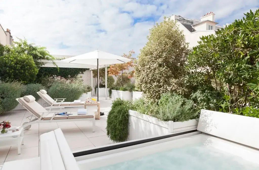 Private Terrasse mit Jacuzzi, Sonnenliegen und Pflanzen im Hotel Le Bristol Paris.
