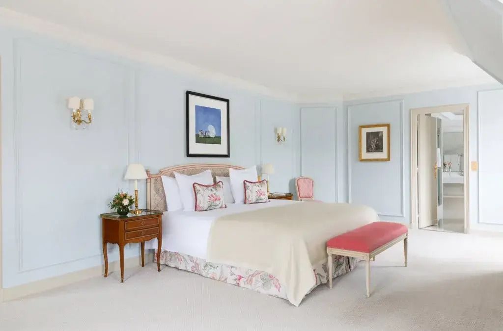 Elegante Suite mit großem Doppelbett und stilvollen Möbeln in sanften Farben.