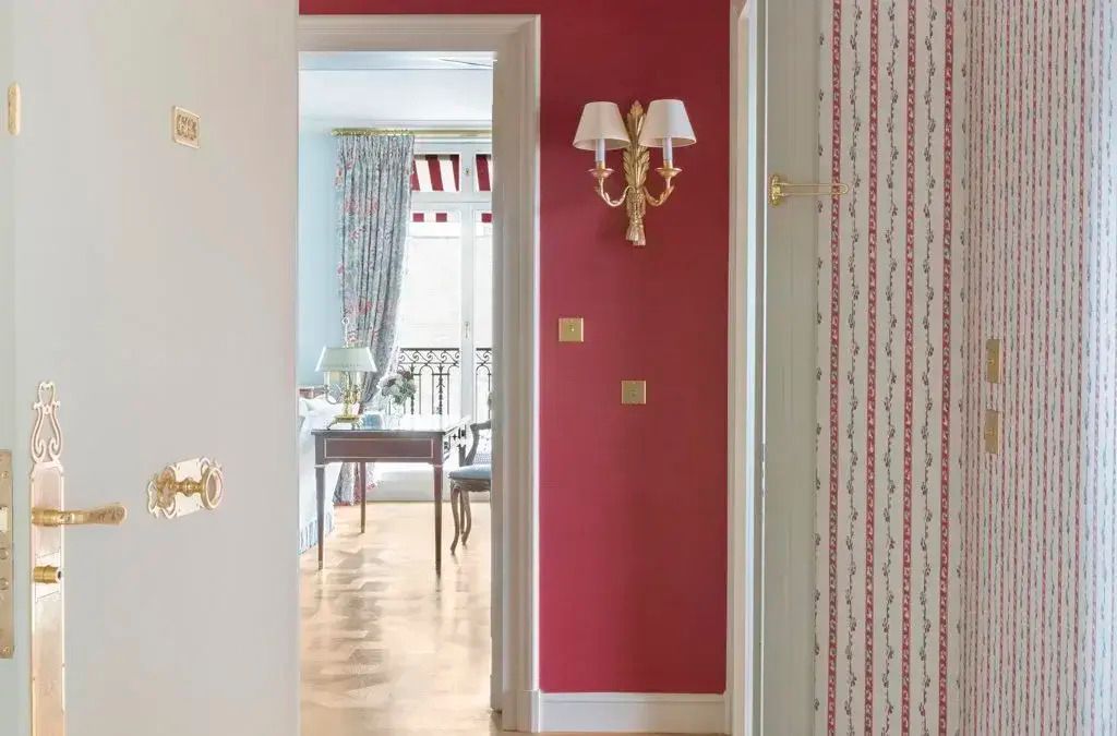 Rot akzentuierte Hotelflurdekoration mit eleganter Wandbeleuchtung.