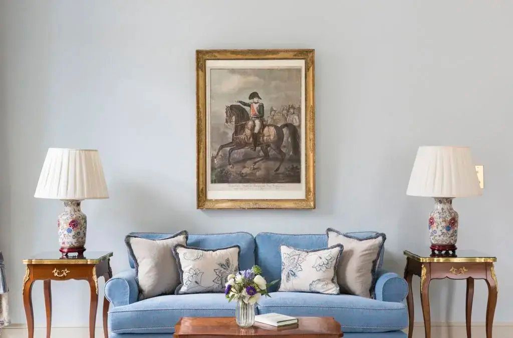 Blaues Sofa mit Kunstgemälde darüber, elegante Einrichtung und Blumenarrangement