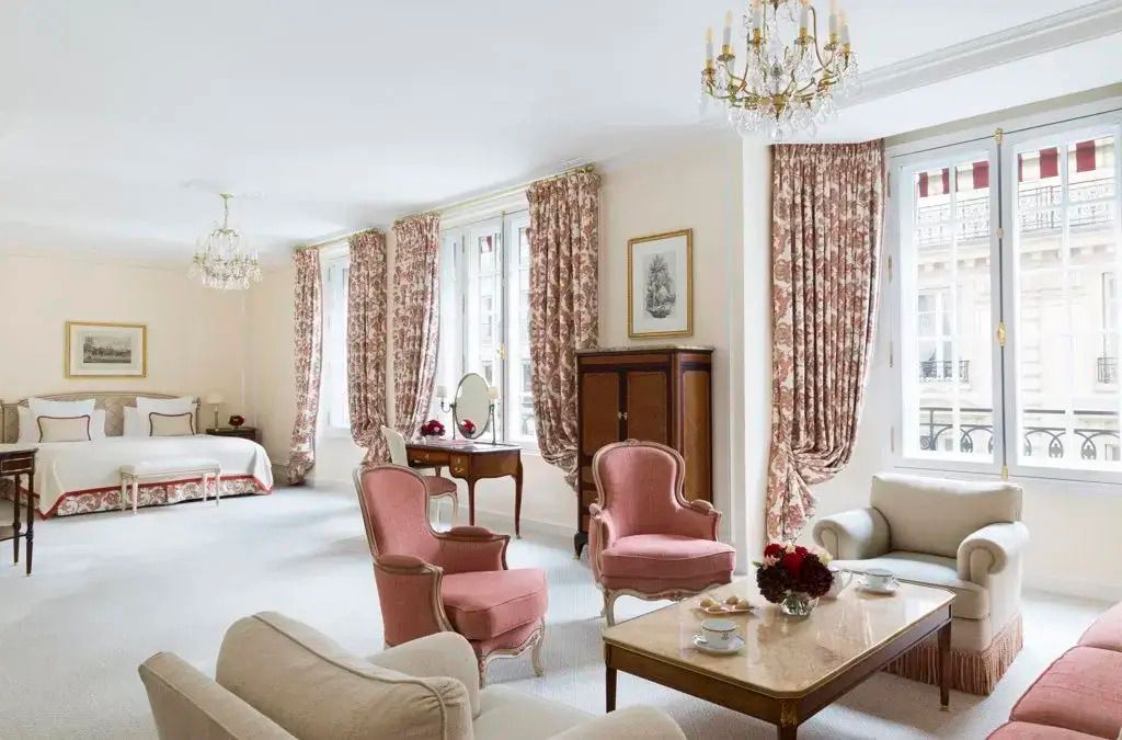 Große Suite mit eleganten Möbeln, rosa Sesseln und Kronleuchtern im Hotel Le Bristol Paris.
