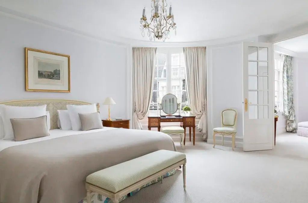 Elegante Suite mit Doppelbett, Kronleuchter und Schminktisch vor einem Fenster