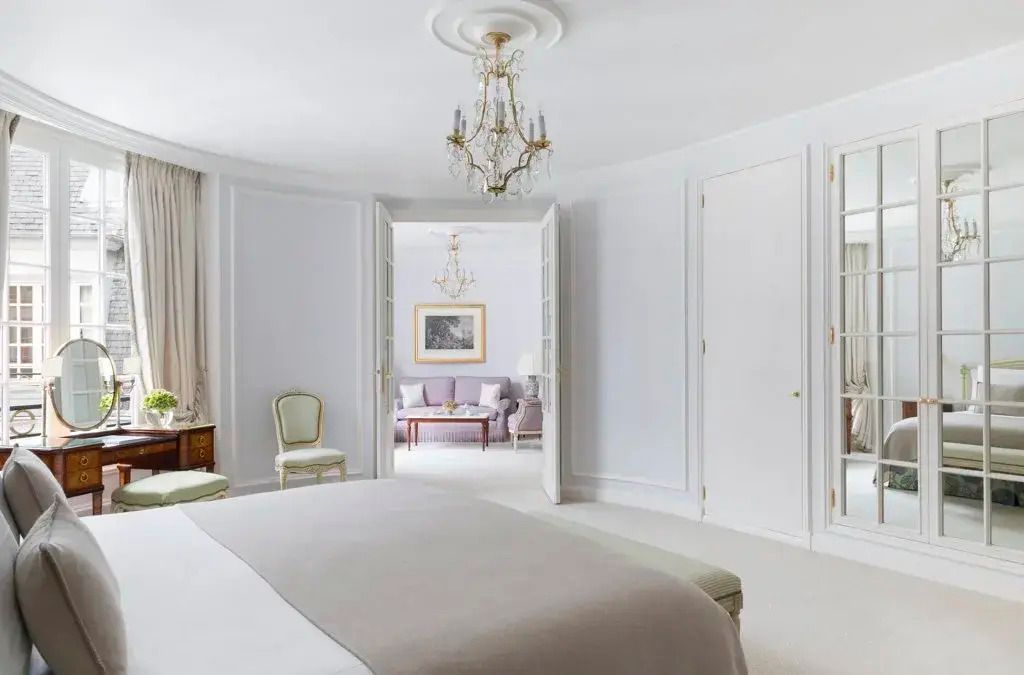 Weißes Schlafzimmer mit Blick in das angrenzende Wohnzimmer durch offene Türen