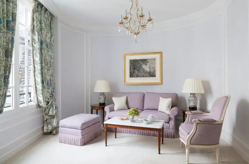 Wohnbereich mit lila Sofa, Marmortisch und klassischen Leuchten
