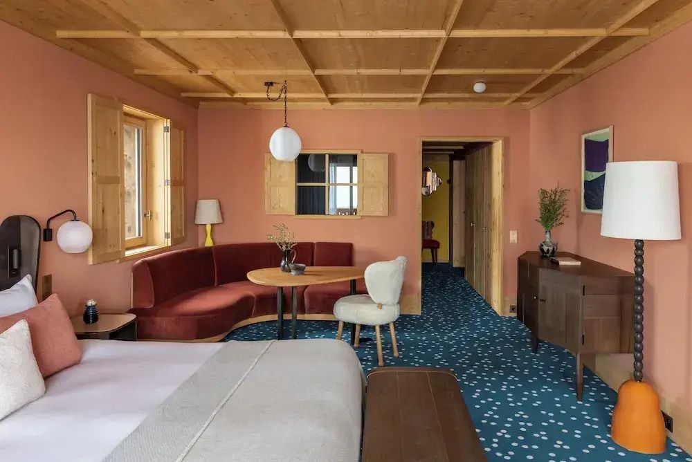 Hotelzimmer mit Holzdecke, Sitzecke und großen Fenstern