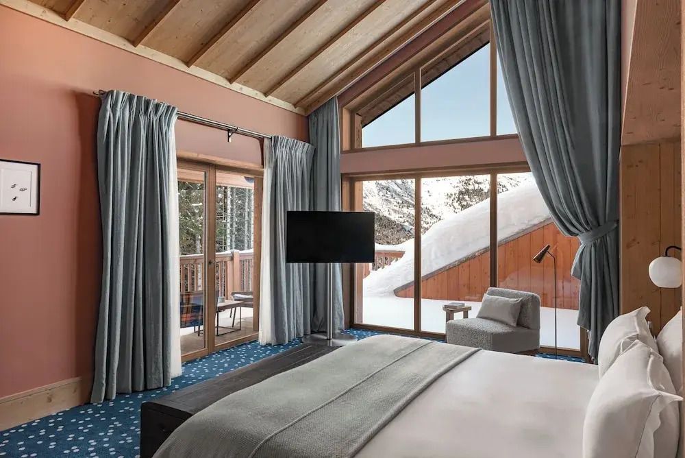 Schlafzimmer mit hohen Decken und Panoramafenstern zur verschneiten Landschaft
