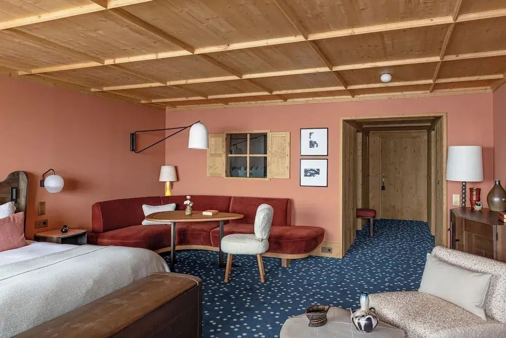 Gemütliche Junior-Suite mit Holzdecke, Sitzbereich und Teppich im Hotel Le Coucou Méribel