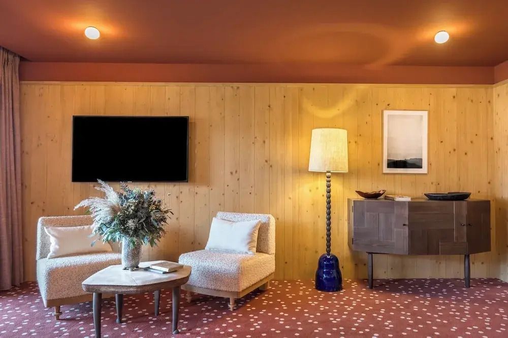 Stilvoll eingerichteter Wohnbereich mit Fernseher und moderner Beleuchtung im Hotel Le Coucou Méribel