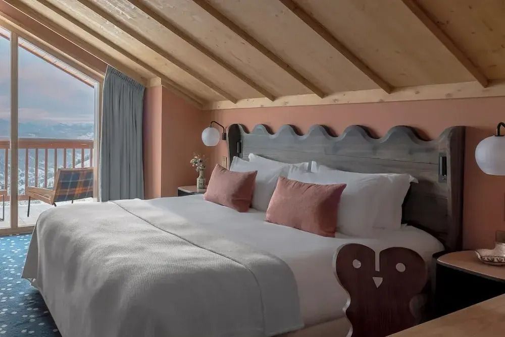 Helles Schlafzimmer in der Prestige Suite mit sichtbaren Deckenbalken und rosa Dekokissen