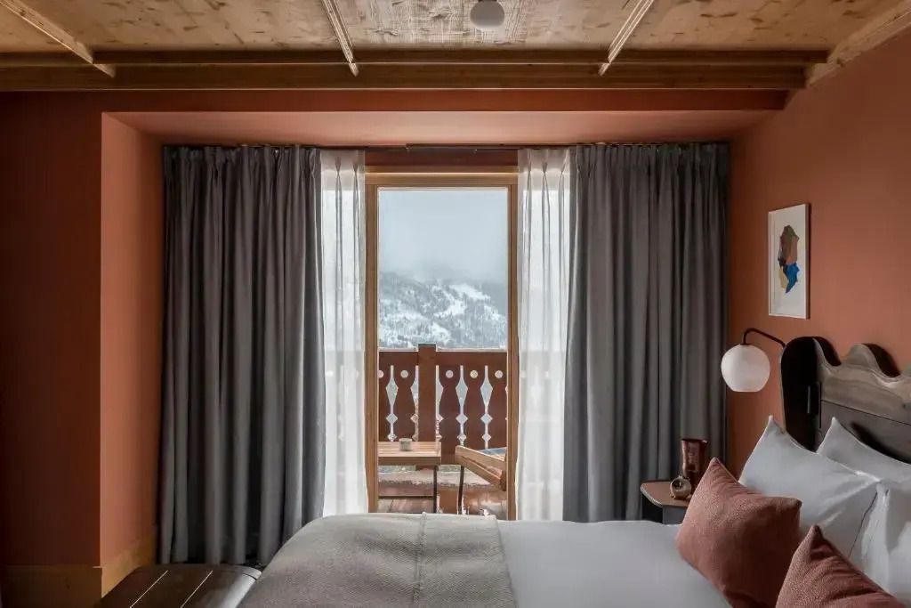 Gemütliches Schlafzimmer mit Vorhängen und Aussicht auf schneebedeckte Berge im Prestige Zimmer