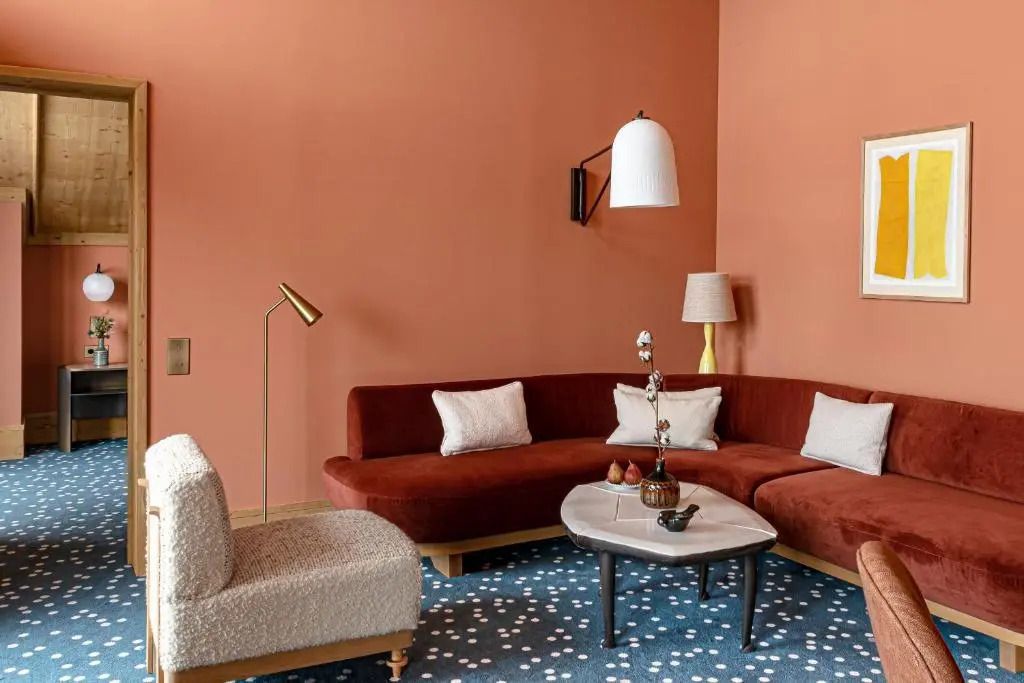 Gemütliche Sitzecke mit rotem Sofa und Designer-Lampen in einem Hotelzimmer