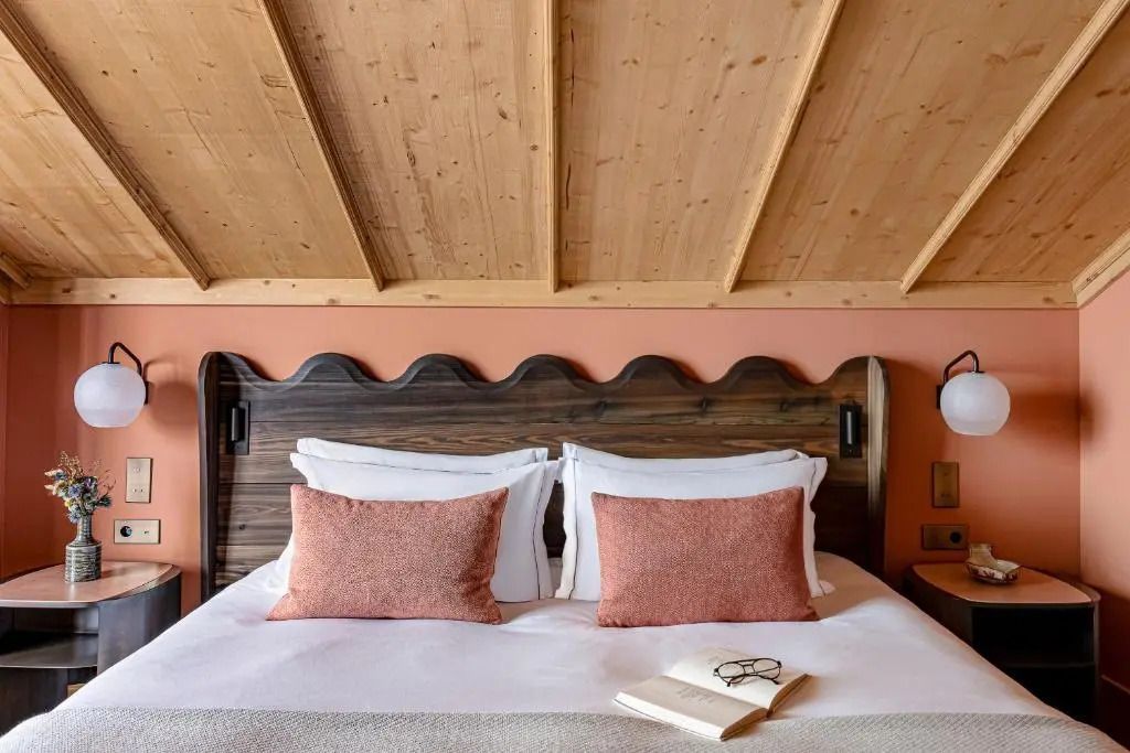 Luxuriöses Bett mit Holzkopfteil und Dachschräge im Hotelzimmer