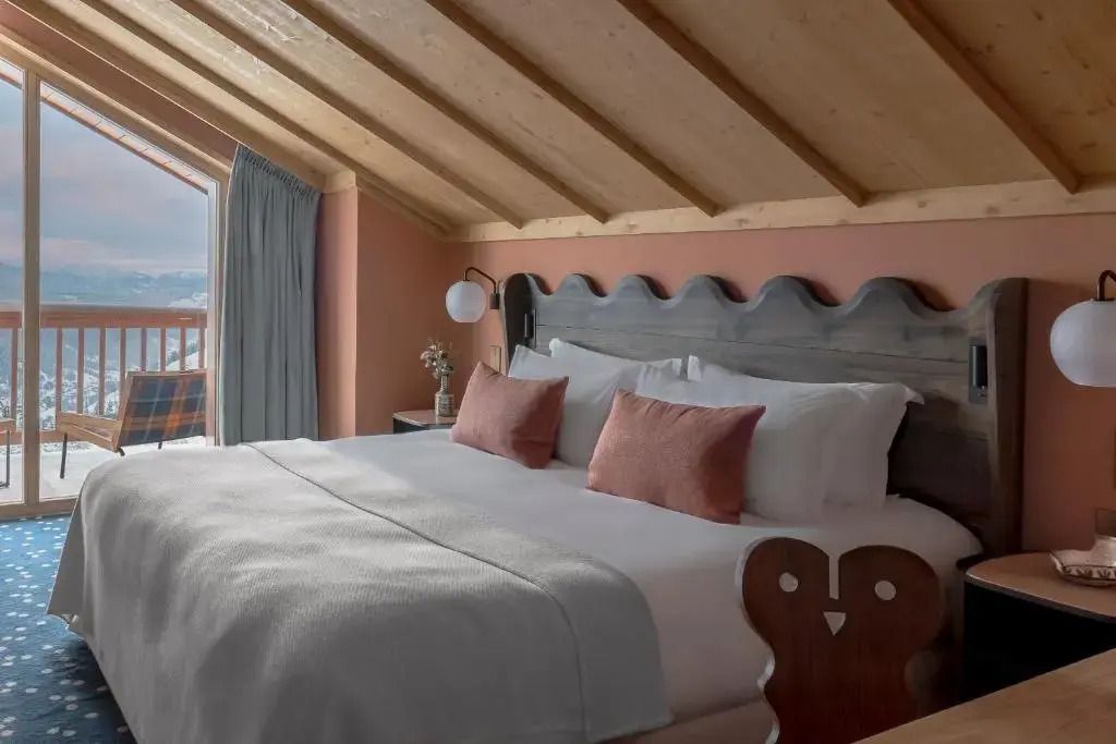 Großes Bett mit Holzdecke und Bergblick im gemütlichen Zimmer